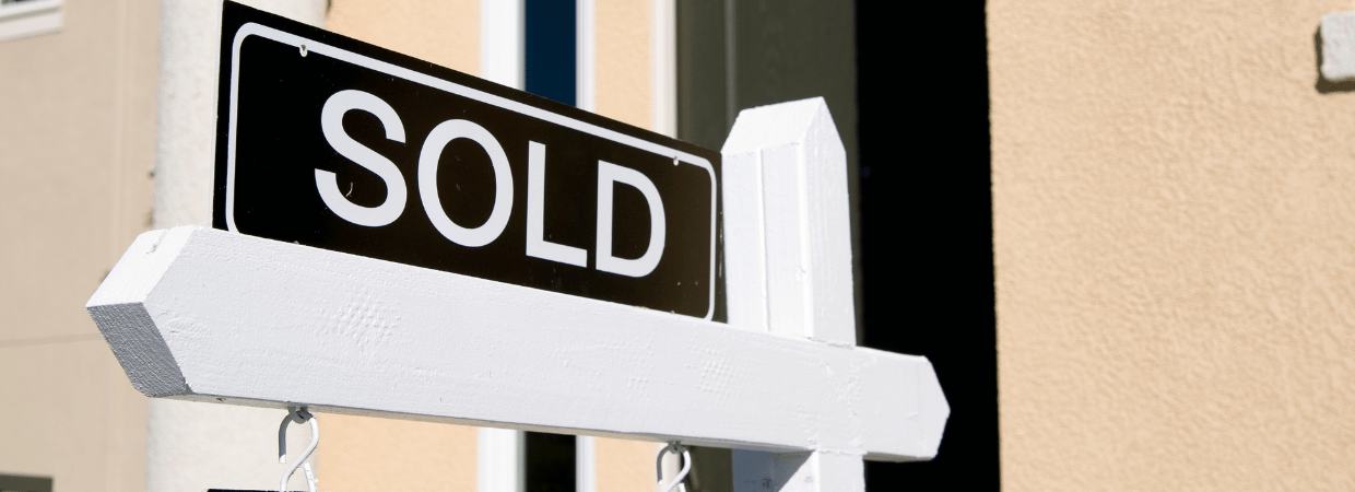A picture of a SOLD sign in front of a home